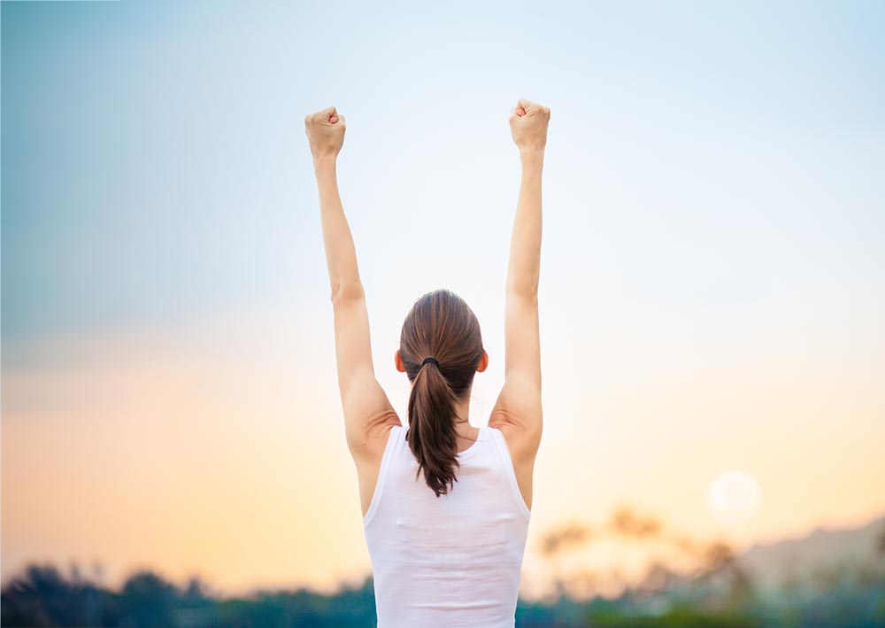 Success and life goals concept. Strong and confident woman with arms in the air.